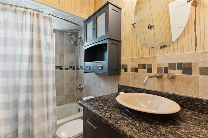 Full bathroom featuring vanity, toilet, shower / bathtub combination with curtain, and tile walls