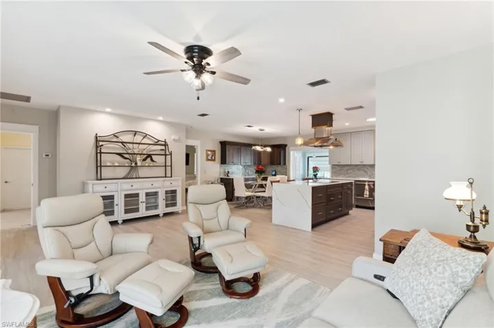 Living room with ceiling fan, light wood-type flooring, and sink