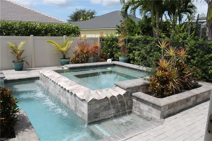 Inviting aquatic feature with a tiered spa, integrated waterfall, and stone-tiled accent wall