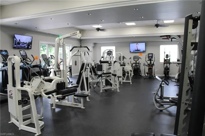 Spacious fitness center featuring a variety of cardio and strength training equipment, durable rubber flooring, recessed lighting, and ceiling fans