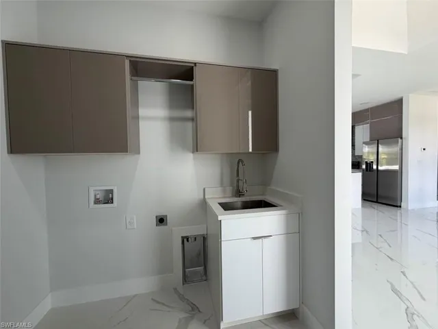 Dedicated laundry space featuring a utility sink, wall-mounted cabinetry, and a chrome faucet