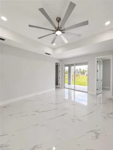Spacious interior featuring a contemporary ceiling fan with integrated lighting, recessed ceiling lights, and tray ceiling detailing