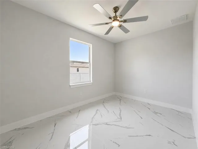 Room featuring large format marble-look tile flooring, a window with white trim, and a ceiling fan with brushed nickel accents