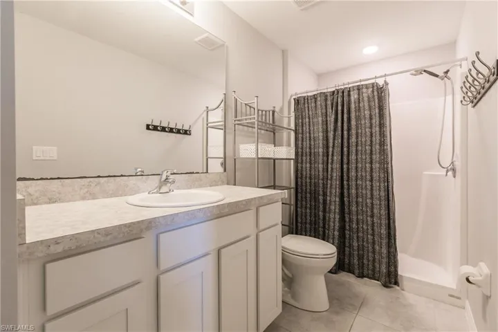 Bathroom with toilet, tile patterned flooring, vanity, and a shower with shower curtain