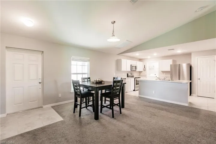 Dining room with light colored carpet, lofted ceiling, and sink