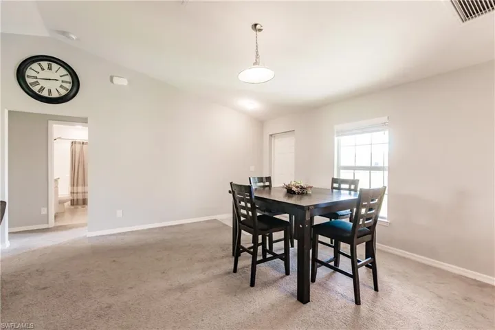 Dining space featuring light carpet and vaulted ceiling