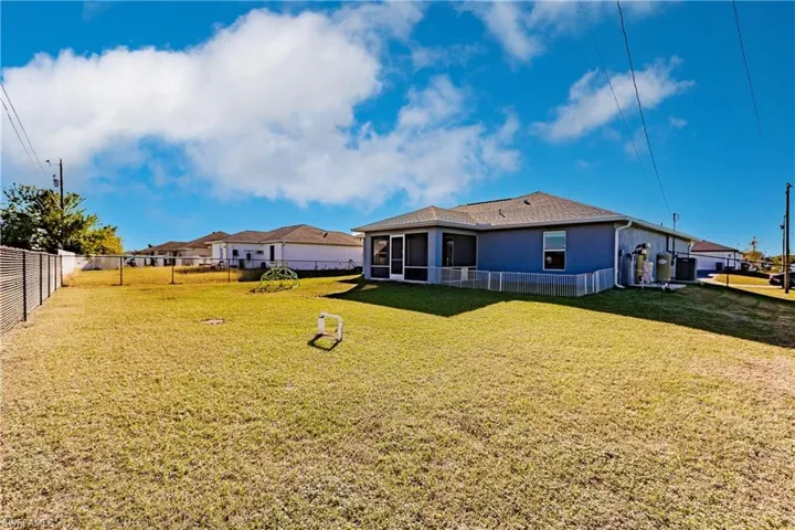 Rear view of property featuring a lawn and a sunroom