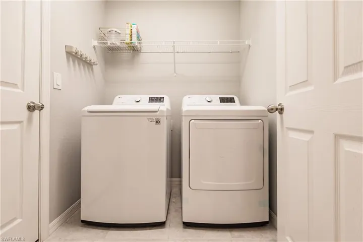 Laundry area featuring washing machine and dryer and light tile patterned floors