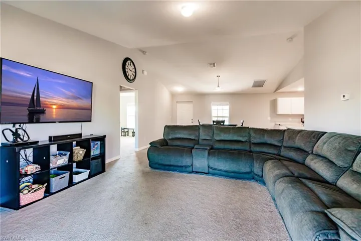 Carpeted living room featuring high vaulted ceiling