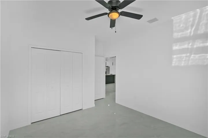 Unfurnished bedroom featuring concrete floors, a ceiling fan, and a closet