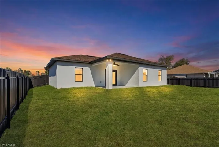 Back of property at dusk with stucco siding, a patio, a fenced backyard, a ceiling fan, and roof with shingles