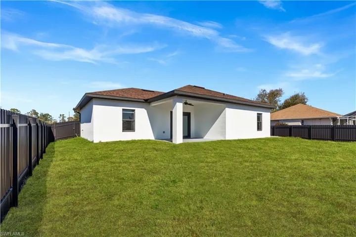 Rear view of house with stucco siding, a patio, a fenced backyard, and roof with shingles