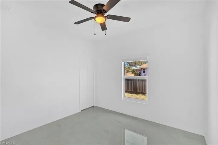 Unfurnished room with finished concrete floors and a ceiling fan