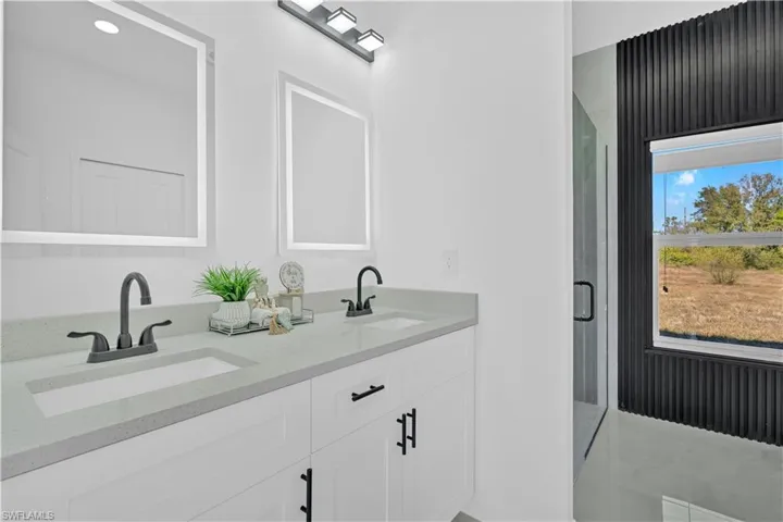 Full bathroom with double vanity, a stall shower, and recessed lighting