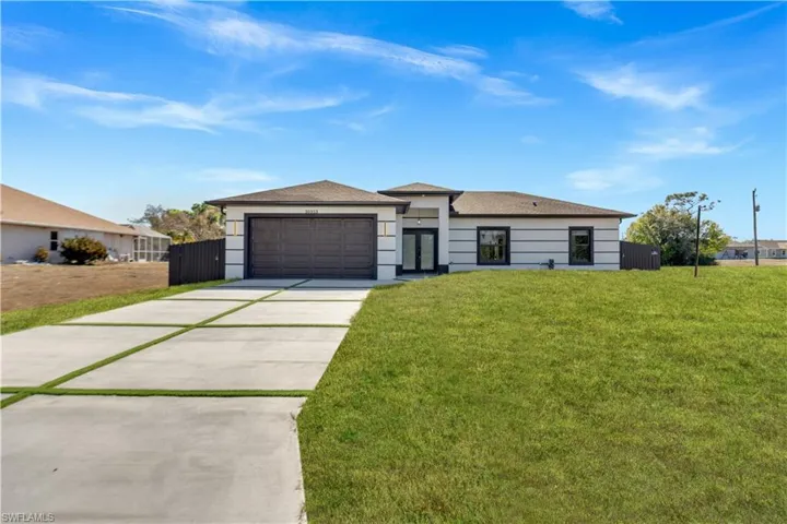 Prairie-style house with driveway, a front lawn, a shingled roof, stucco siding, and a garage