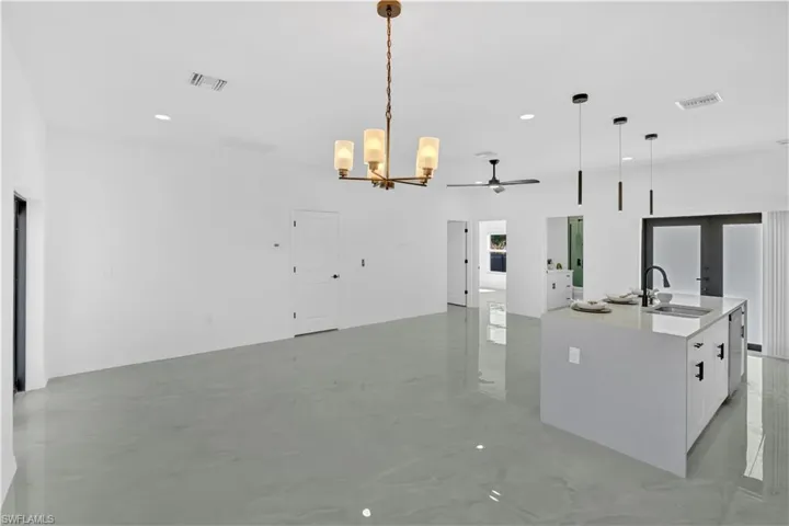 Kitchen featuring a chandelier, open floor plan, light stone countertops, hanging light fixtures, and recessed lighting