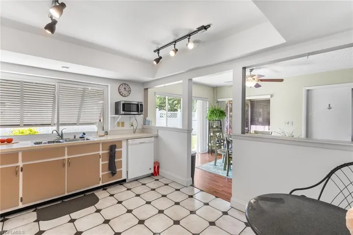 Kitchen featuring white dishwasher, stainless steel microwave, rail lighting, and a ceiling fan