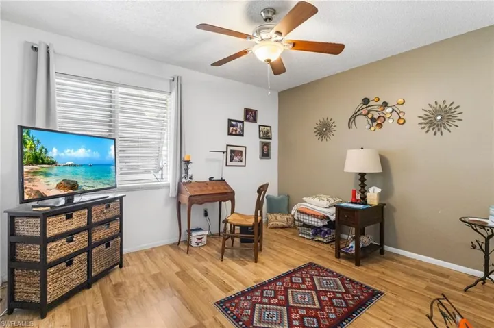 Sitting room featuring a ceiling fan, light wood finished floors, and a textured ceiling