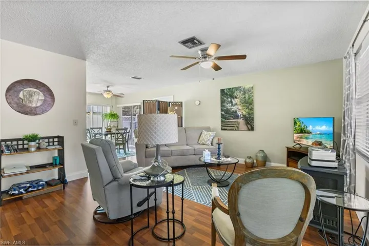 Living area featuring a ceiling fan, wood finished floors, and a textured ceiling