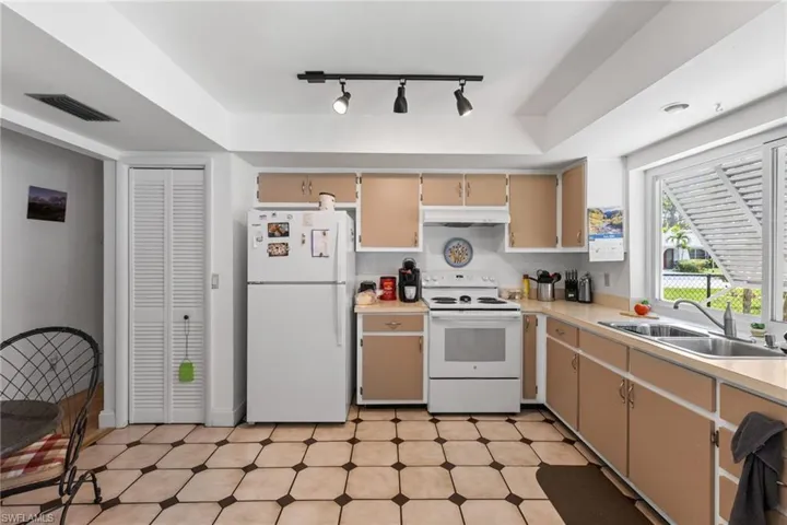 Kitchen featuring white appliances, under cabinet range hood, track lighting, and light flooring
