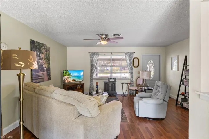 Living area featuring ceiling fan, dark wood-style floors, and a textured ceiling