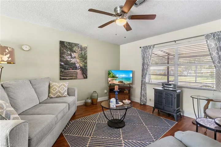 Living room featuring a ceiling fan, a textured ceiling, and wood finished floors