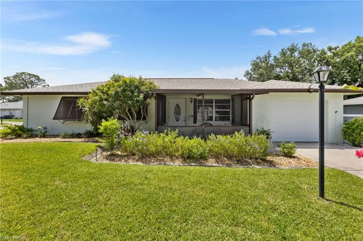 Ranch-style house featuring a garage, a front lawn, concrete driveway, and stucco siding
