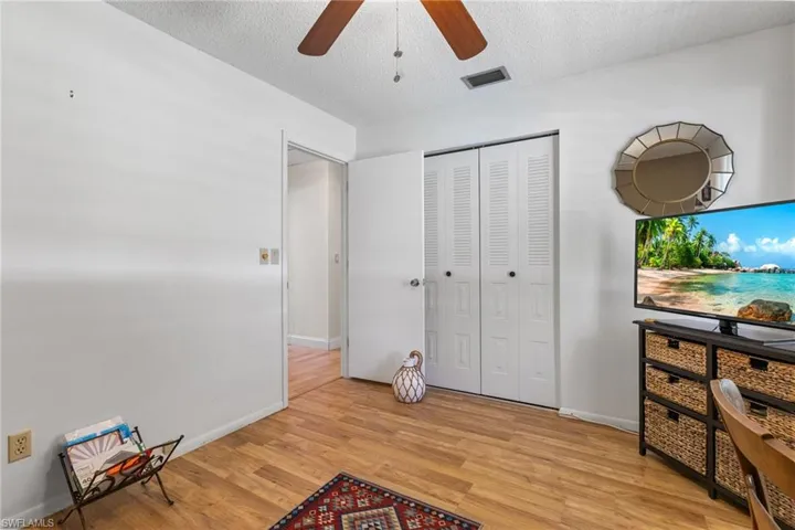 Unfurnished bedroom featuring light wood finished floors, a closet, a textured ceiling, and ceiling fan