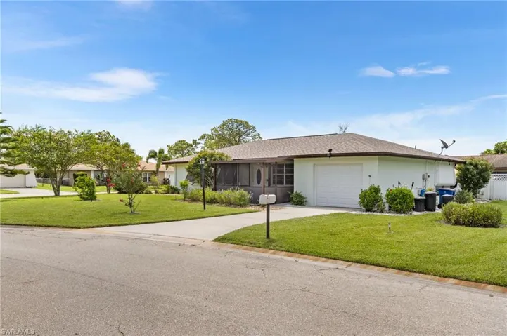 Ranch-style home with concrete driveway, an attached garage, a front lawn, and stucco siding