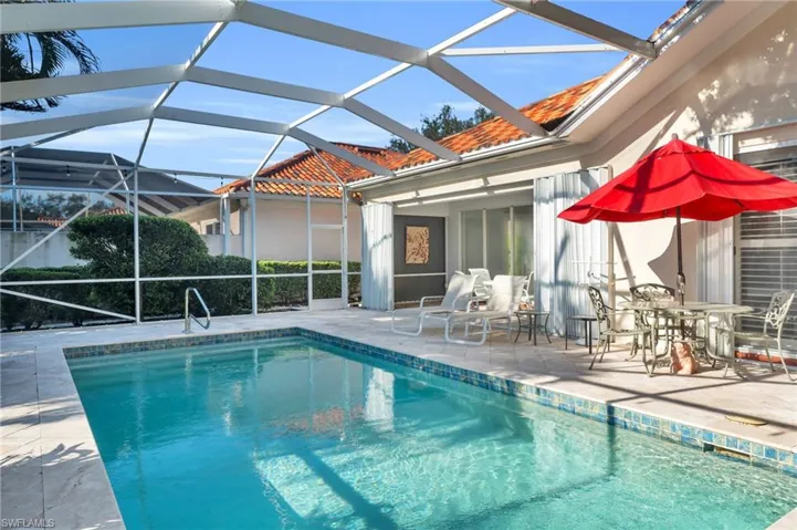 View of swimming pool with glass enclosure and a patio area