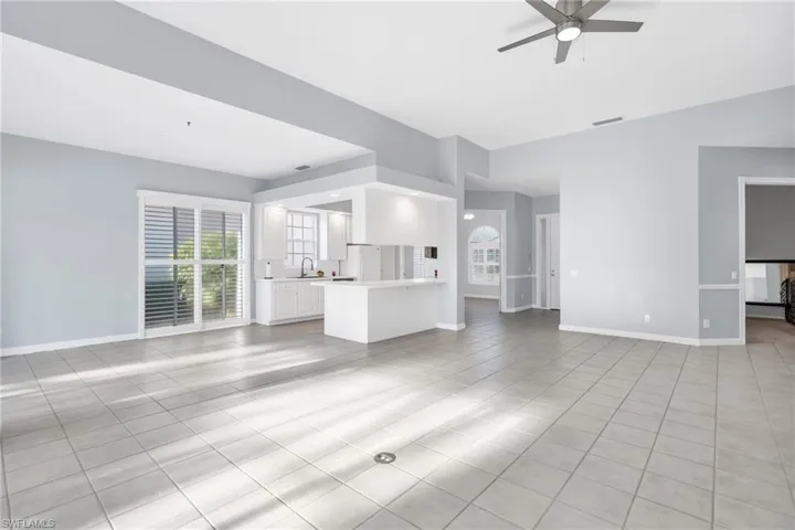 Unfurnished living room with ceiling fan, sink, and light tile patterned floors