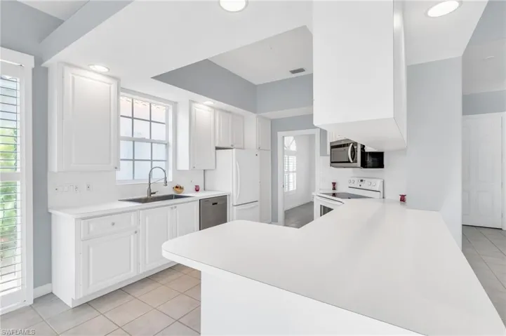Kitchen with a healthy amount of sunlight, stainless steel appliances, white cabinets, and sink