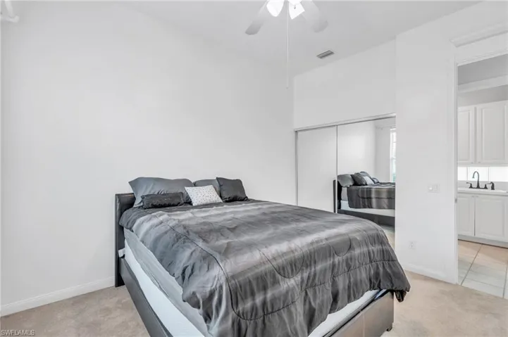 Carpeted bedroom with ceiling fan and sink
