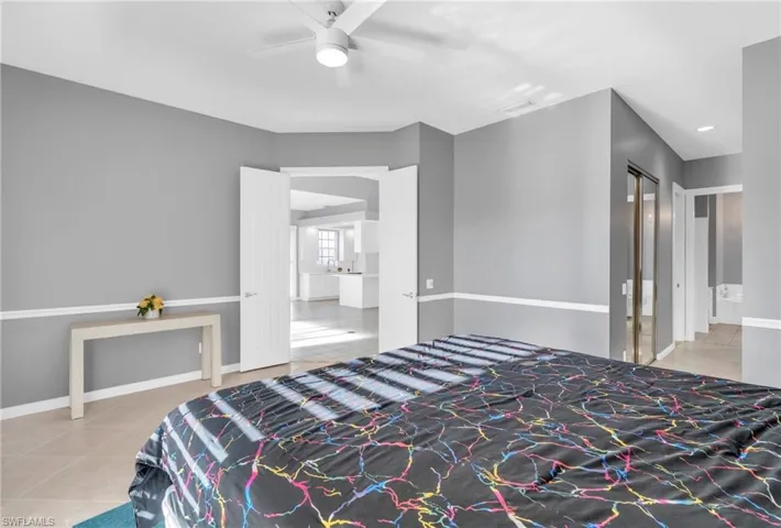 Bedroom with ensuite bath, ceiling fan, and tile patterned floors