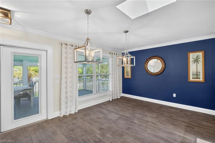 Large dining area with a deep blue accent wall, two open-cage pendant light fixtures, and lots of natural light