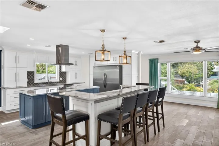 Spacious kitchen featuring two islands with contrasting cabinetry, stainless steel appliances, and bar seating.
