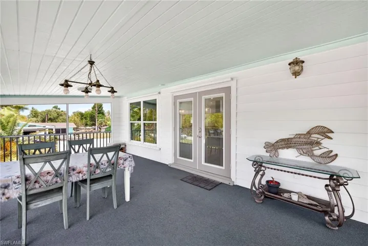 Screen front porch has plank ceiling, dual French doors, a large picture window, and full-height railing.
