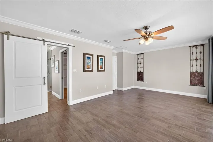 A white barn door leads to the spacious primary bathroom that has a large walk in closet