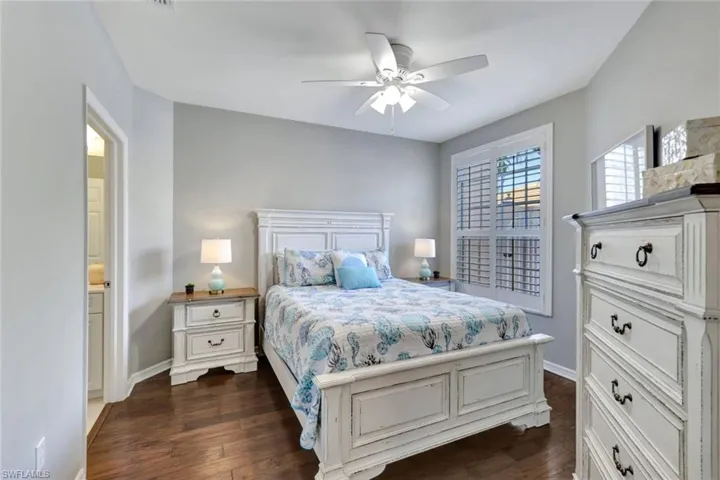Guest bedroom with bath, ceiling fan and dark hardwood flooring.