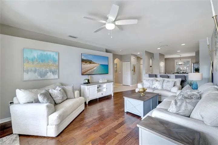 Living room featuring rich hardwood floors and lighted ceiling fan