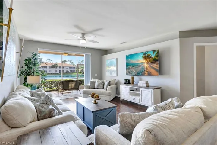 Living room featuring dark hardwood floors, ceiling fan and lanai with westerly sunset lake views!