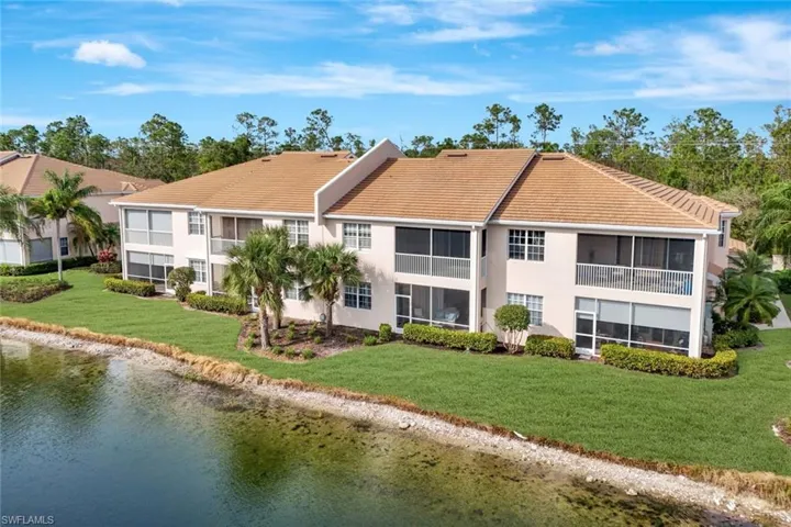 Rear view of condo home featuring lawn, palms, privacy landscaping and sparkling water views!