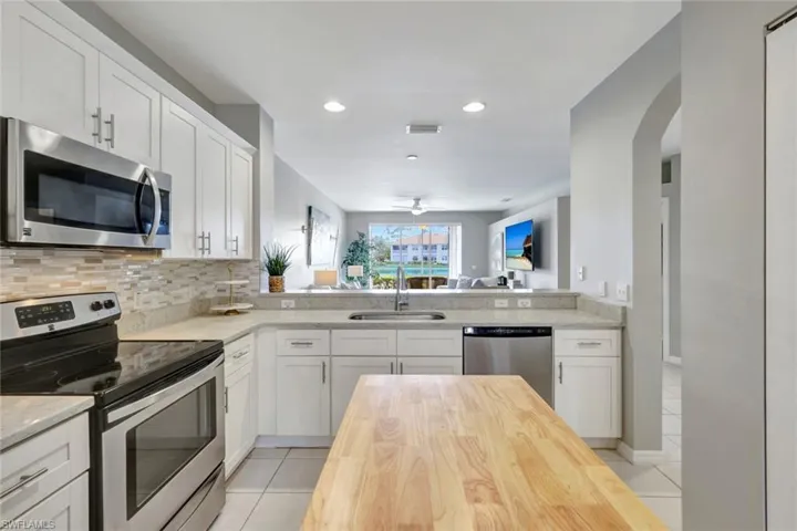 Functional kitchen with backsplash, sink overlooking LR, lanai and blue lake views! Quality shaker white cabinetry,  stainless steel appliances and butcher block island.