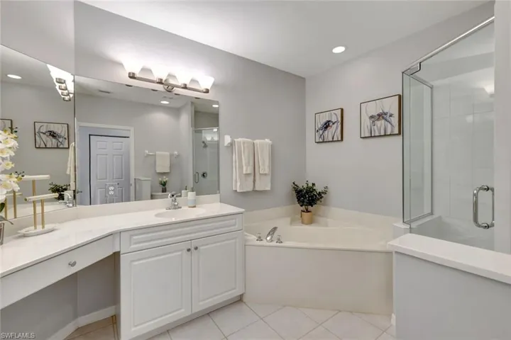 Primary bathroom featuring neutral tile floors, vanity, plus separate shower and tub