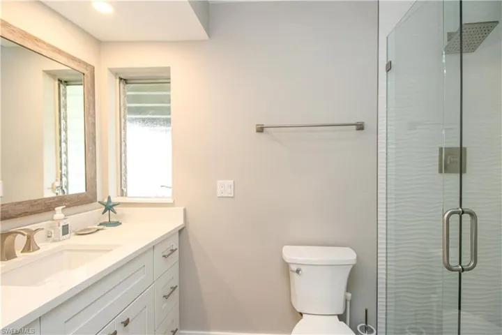 Bathroom with vanity, toilet, and an enclosed shower