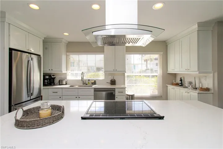 Kitchen with white cabinets, appliances with stainless steel finishes, island range hood, and sink