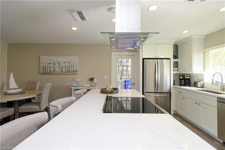 Kitchen with white cabinets, sink, dark hardwood / wood-style floors, appliances with stainless steel finishes, and light stone counters