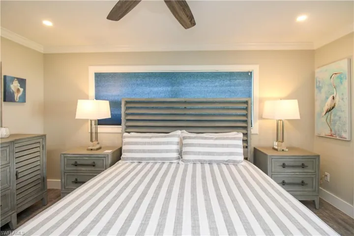 Bedroom with ceiling fan, crown molding, and dark wood-type flooring