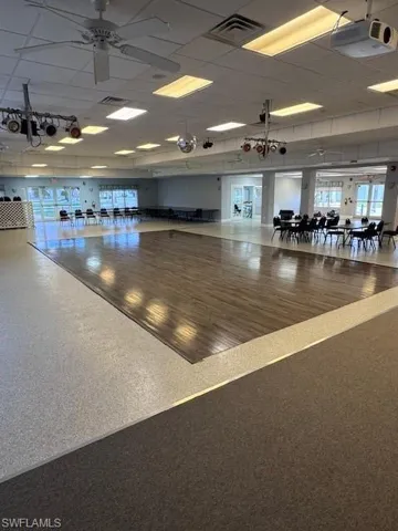 Spacious multi-purpose room with wood-finish flooring, ceiling fans, recessed lighting, and large windows