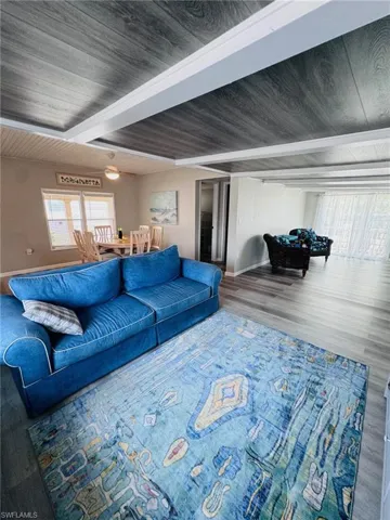Wood-finish flooring throughout, tray ceiling with wood-finish panels, dining area with windows, built-in ceiling fan, and recessed lighting